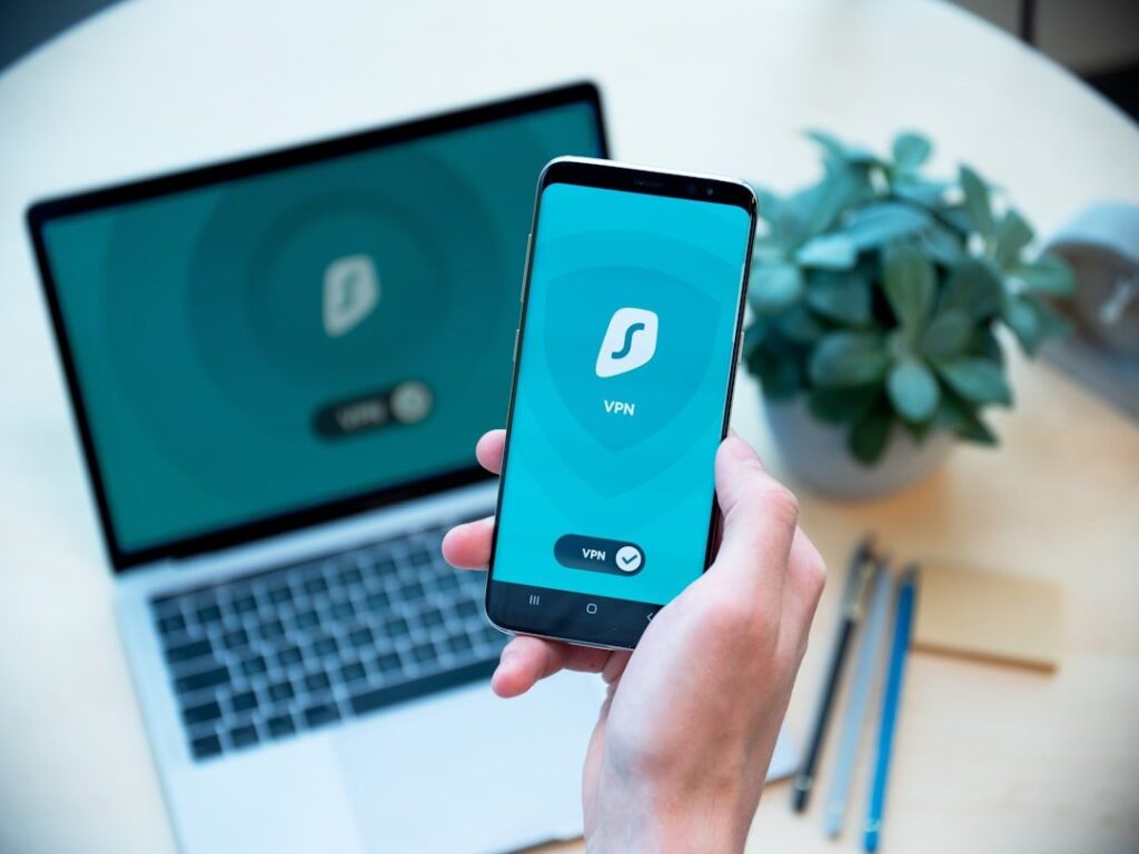 Persona usando una VPN en su teléfono frente a una laptop